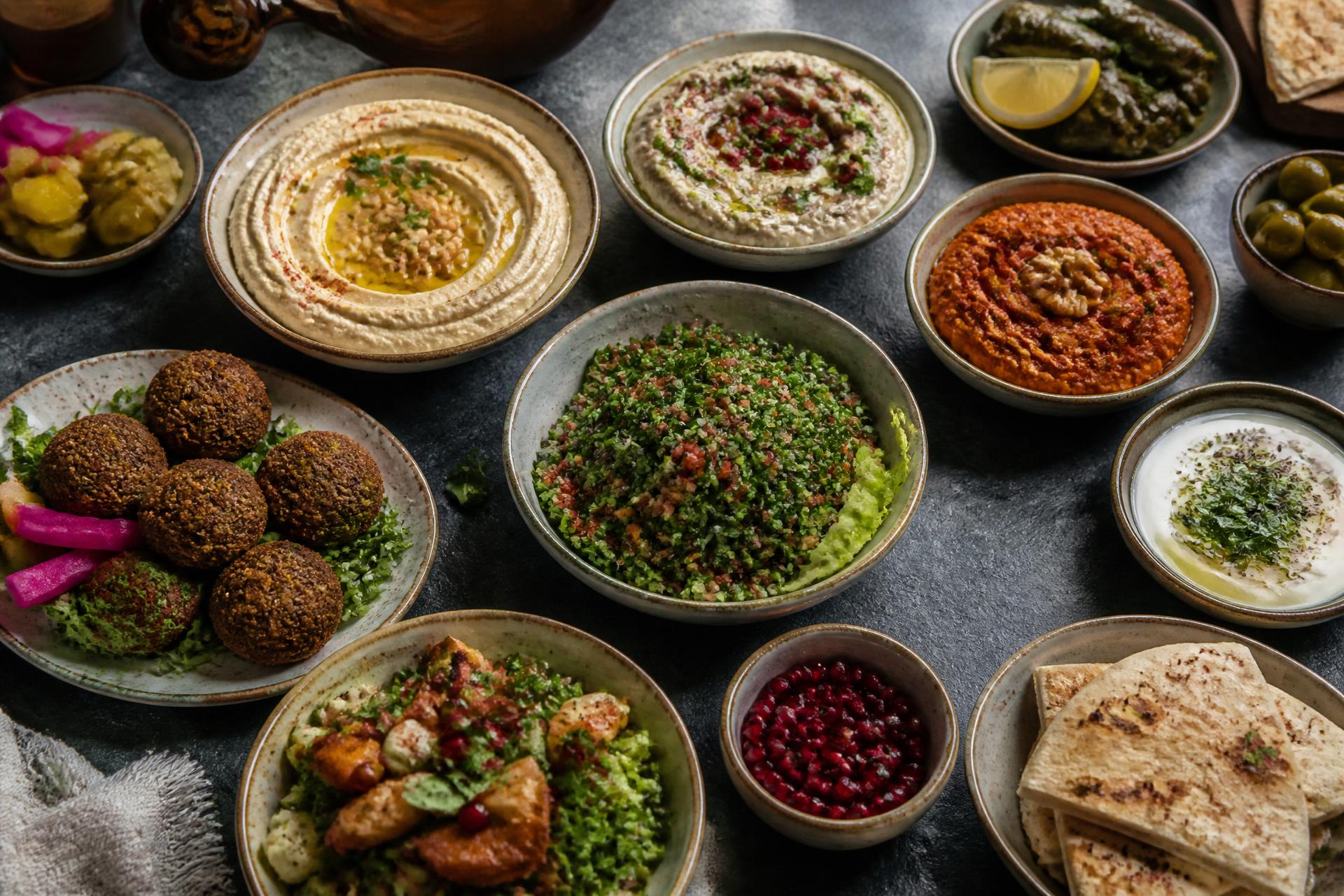 Mesa llena de mezzes libaneses: hummus, muhammara, tabbouli, falafel y pan