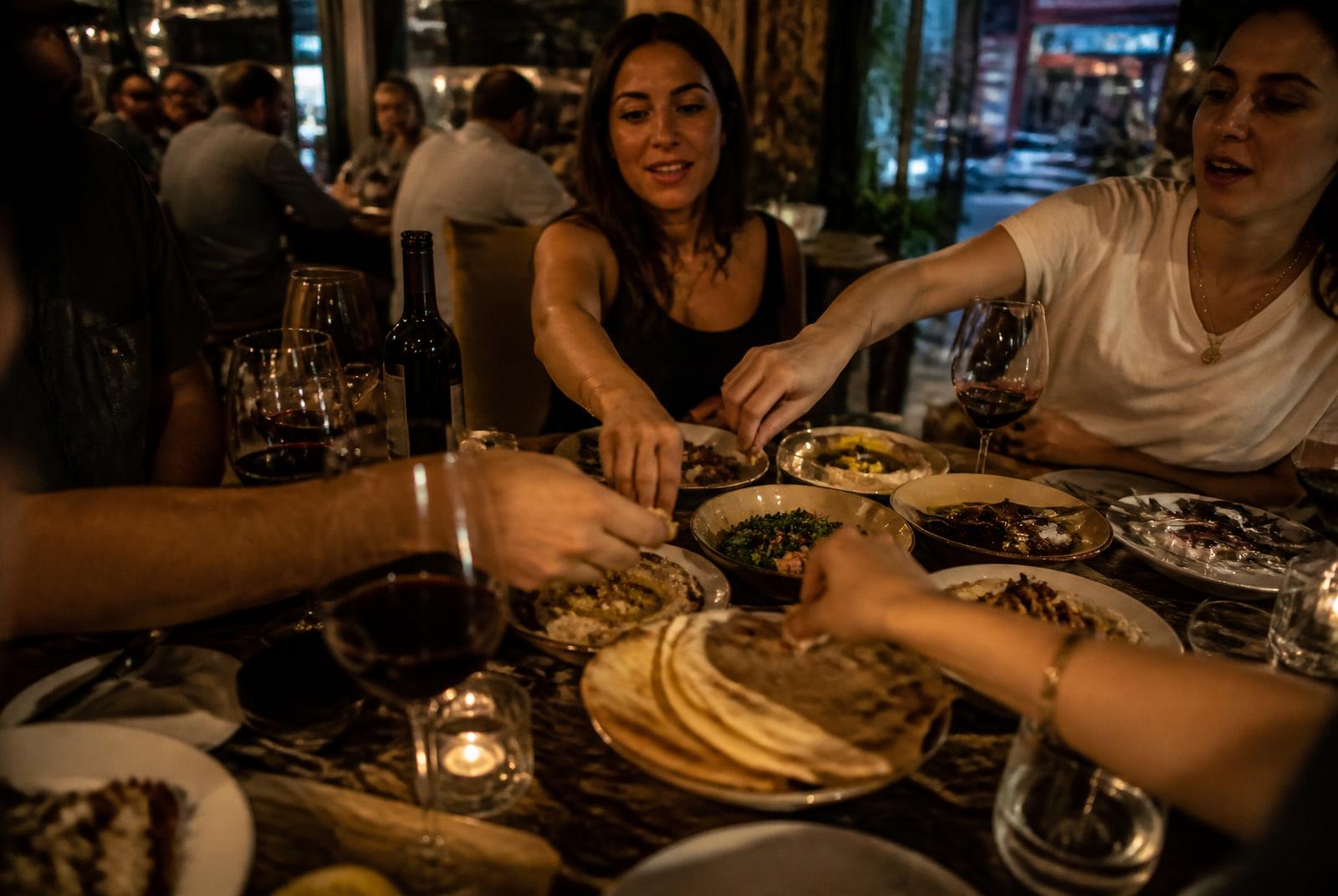 Manos compartiendo platos libaneses en la mesa